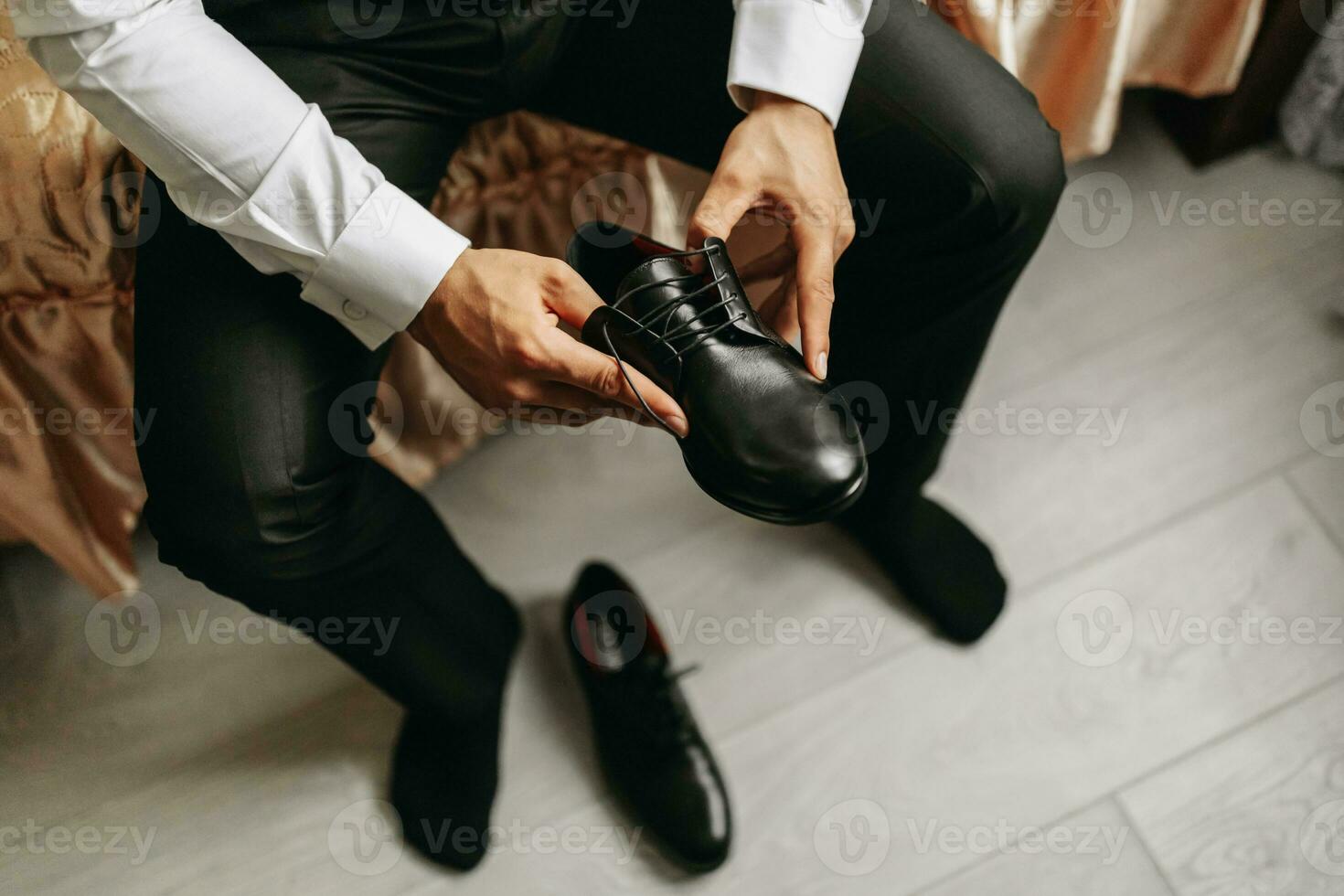 une homme dans une blanc chemise, laçage noir des chaussures et en train de préparer à rencontrer le sien la mariée. le homme porte classique noir des chaussures photo