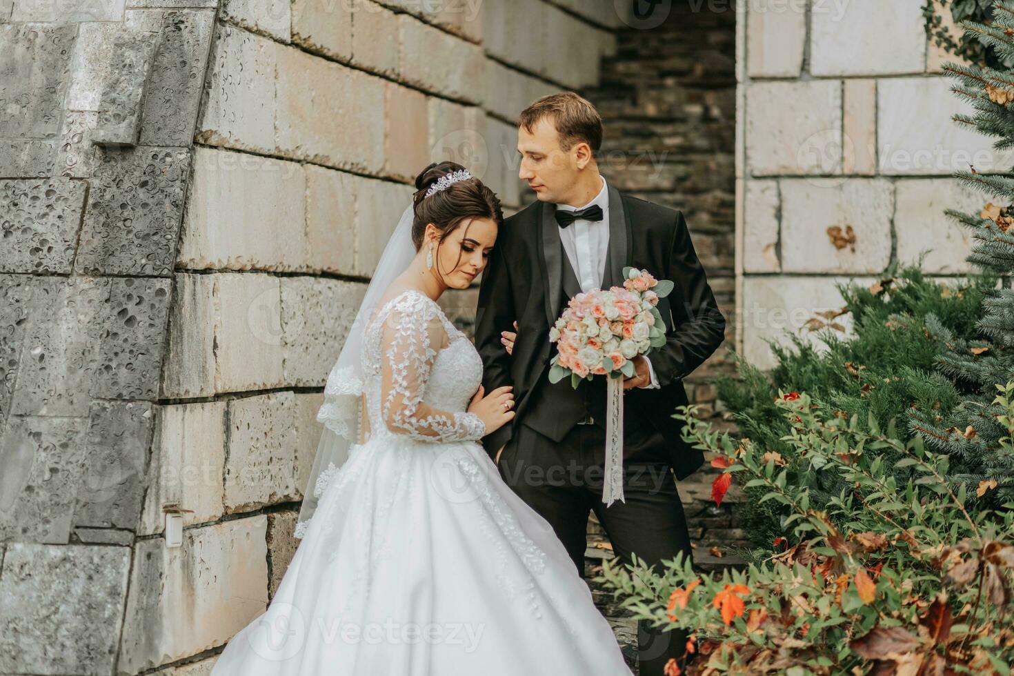 une content couple de élégant jeunes mariés dans une vert parc sur un l'automne journée. le la mariée dans une longue blanc robe et le jeune marié dans une noir costume. portrait de le la mariée et jeune marié sur leur mariage journée. photo