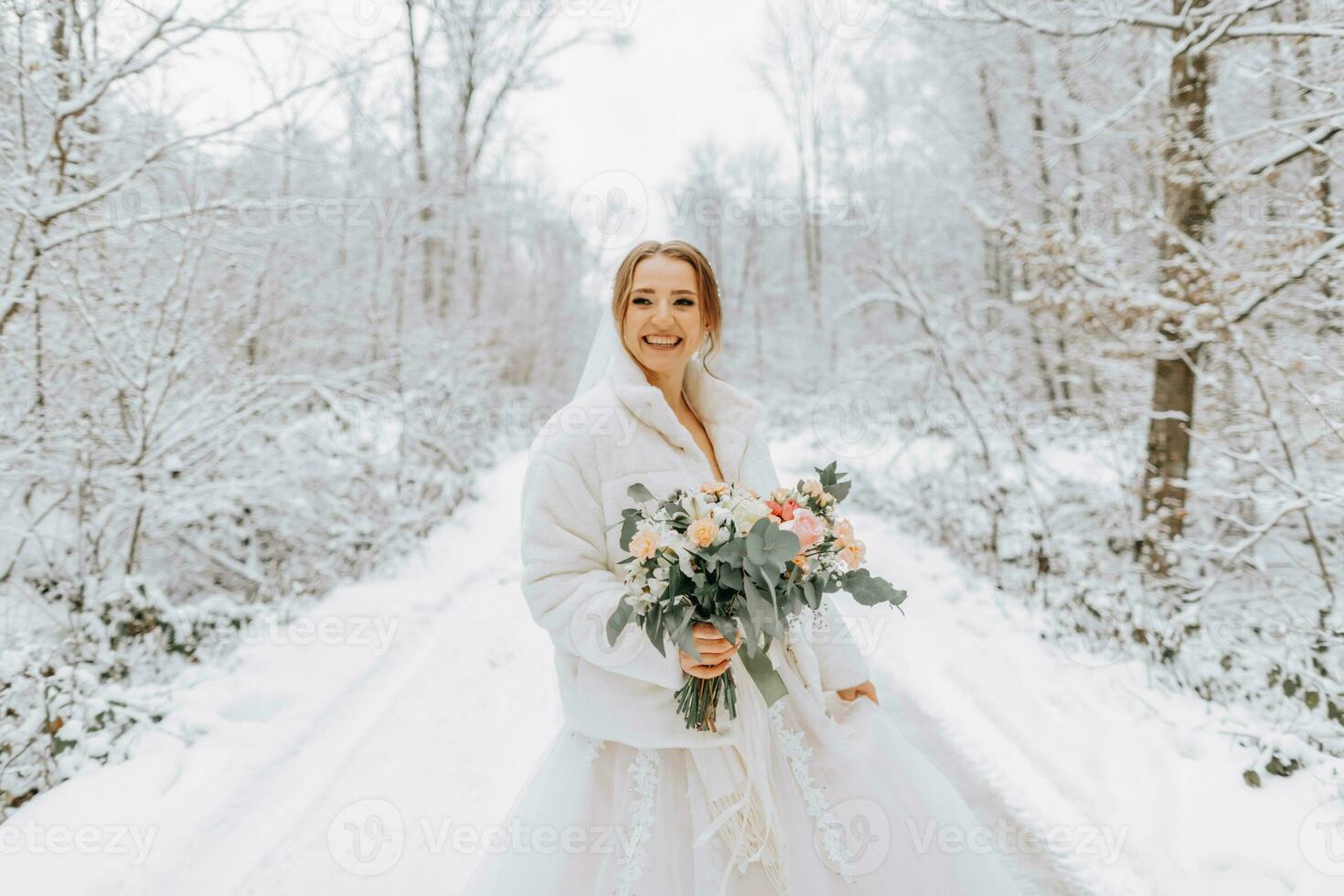 une magnifique la mariée dans une blanc robe avec une bouquet de fleurs dans une fabuleux neigeux hiver forêt. portrait de le la mariée dans la nature. photo