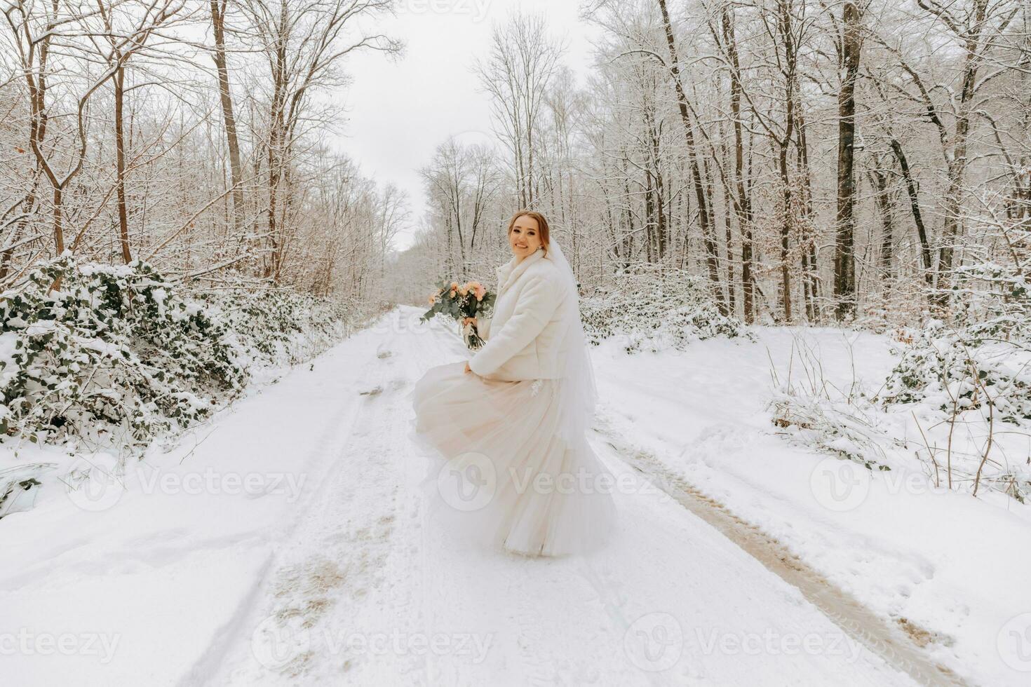 une magnifique la mariée dans une blanc robe avec une bouquet de fleurs dans une fabuleux neigeux hiver forêt. portrait de le la mariée dans la nature. magnifique la mariée dans une blanc robe dans une hiver forêt. photo