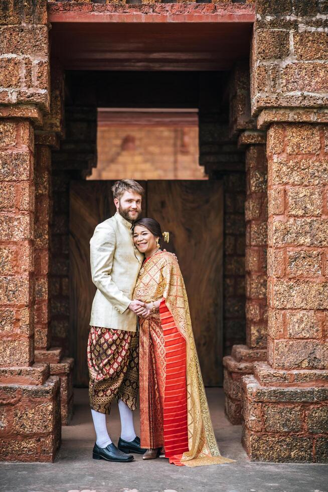 la mariée asiatique et le marié caucasien passent un moment romantique avec une robe thaïlandaise photo