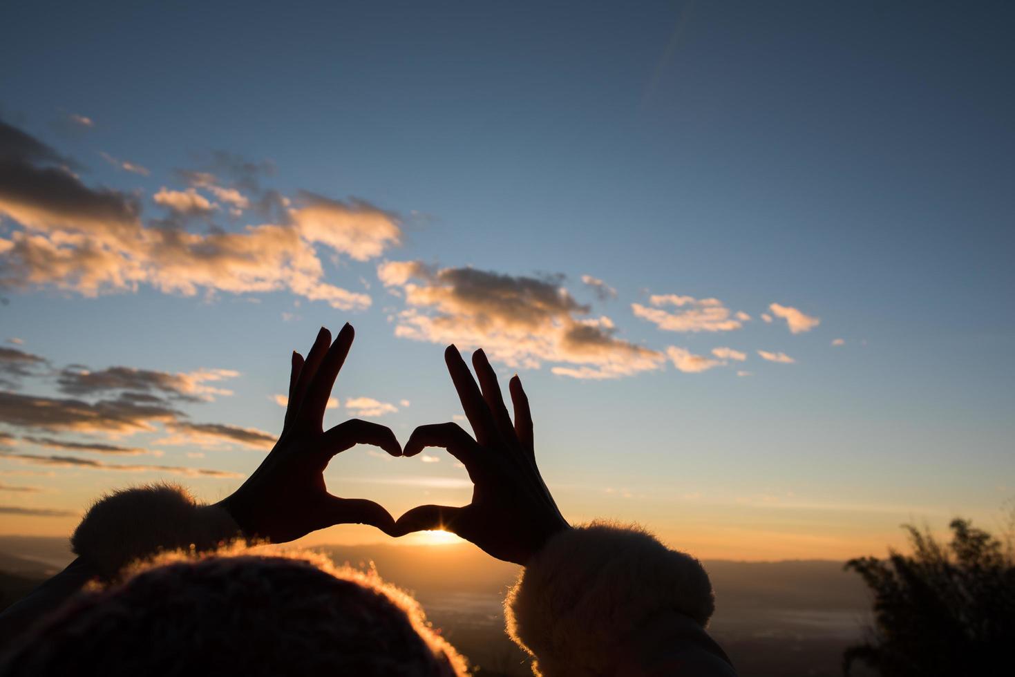 mains silhouette formant une forme de coeur avec le lever du soleil photo