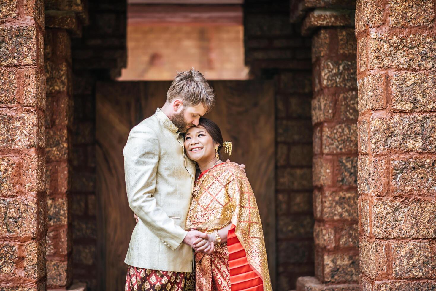 la mariée asiatique et le marié caucasien passent un moment romantique avec une robe thaïlandaise photo