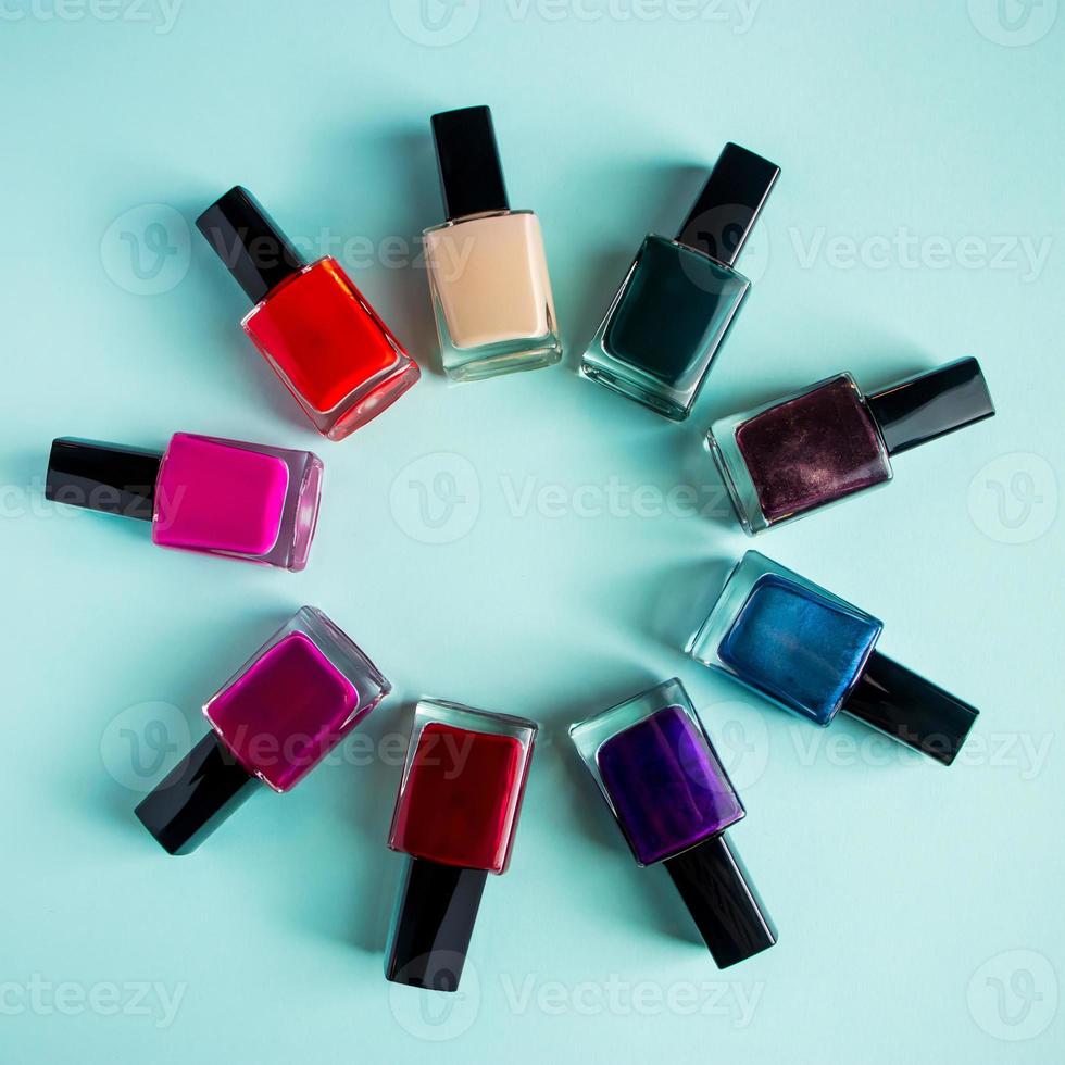 groupe de vernis à ongles de couleur vive sur fond bleu. ensemble de cosmétiques décoratifs pour les soins du corps. photo