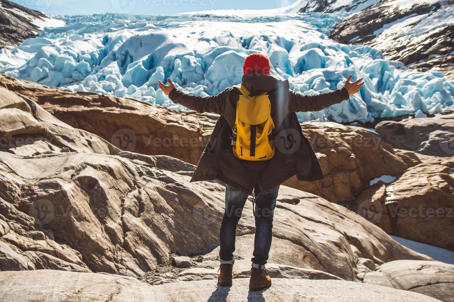 homme voyageur debout sur un rocher sur fond de glacier, de montagnes et de neige photo