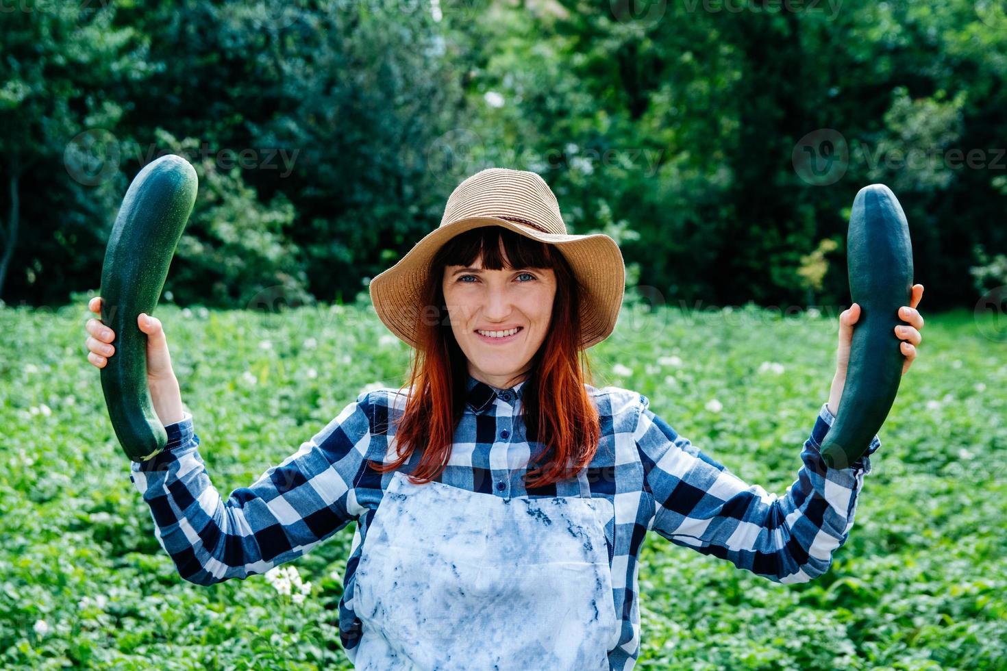 Une agricultrice tient une courgette dans son potager photo