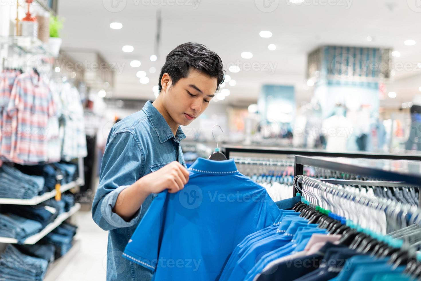 l'homme asiatique intelligent choisit des vêtements dans le magasin de vêtements du centre commercial, photo