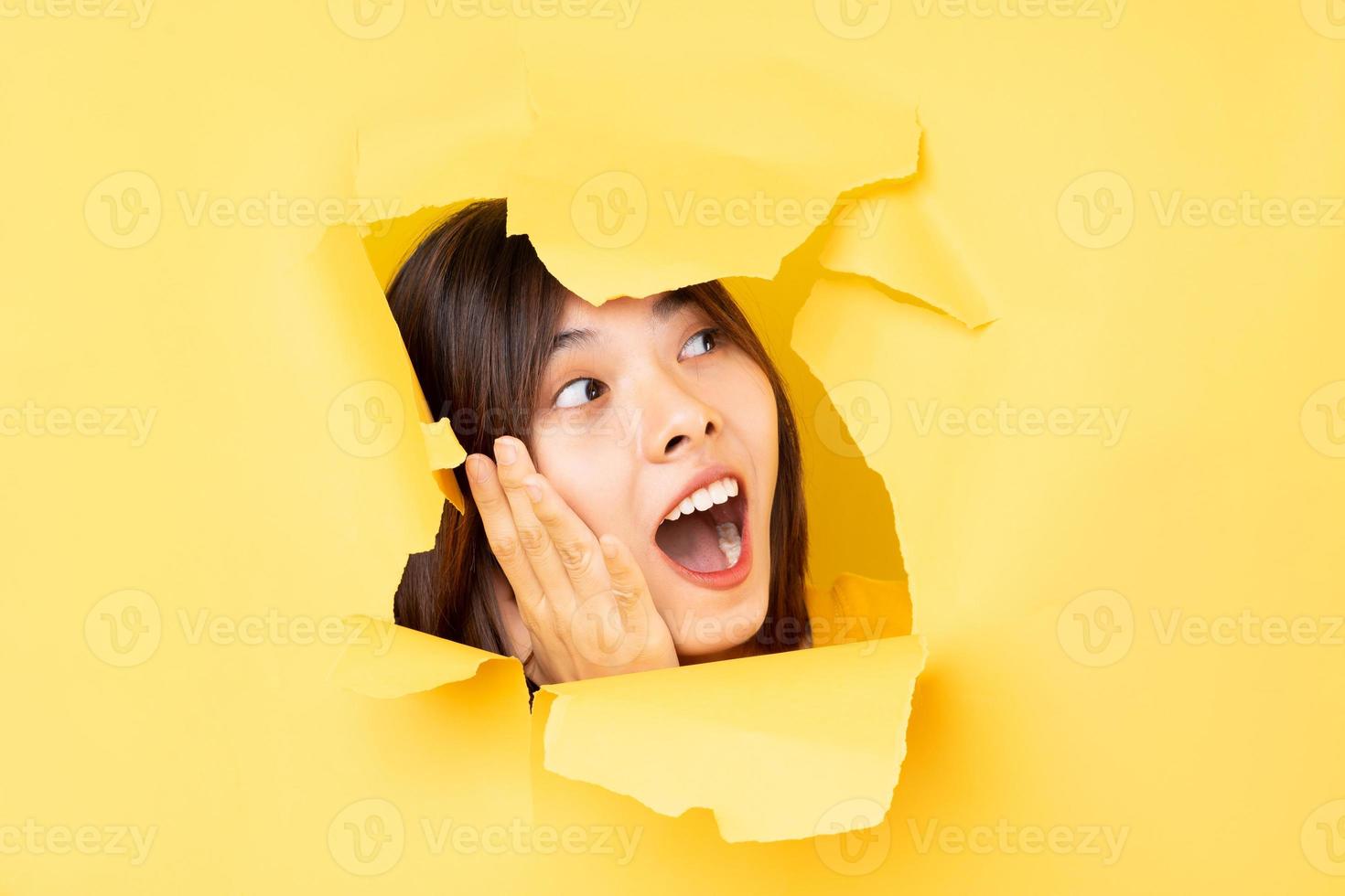 une jeune femme asiatique a passé la tête à travers le papier déchiré photo
