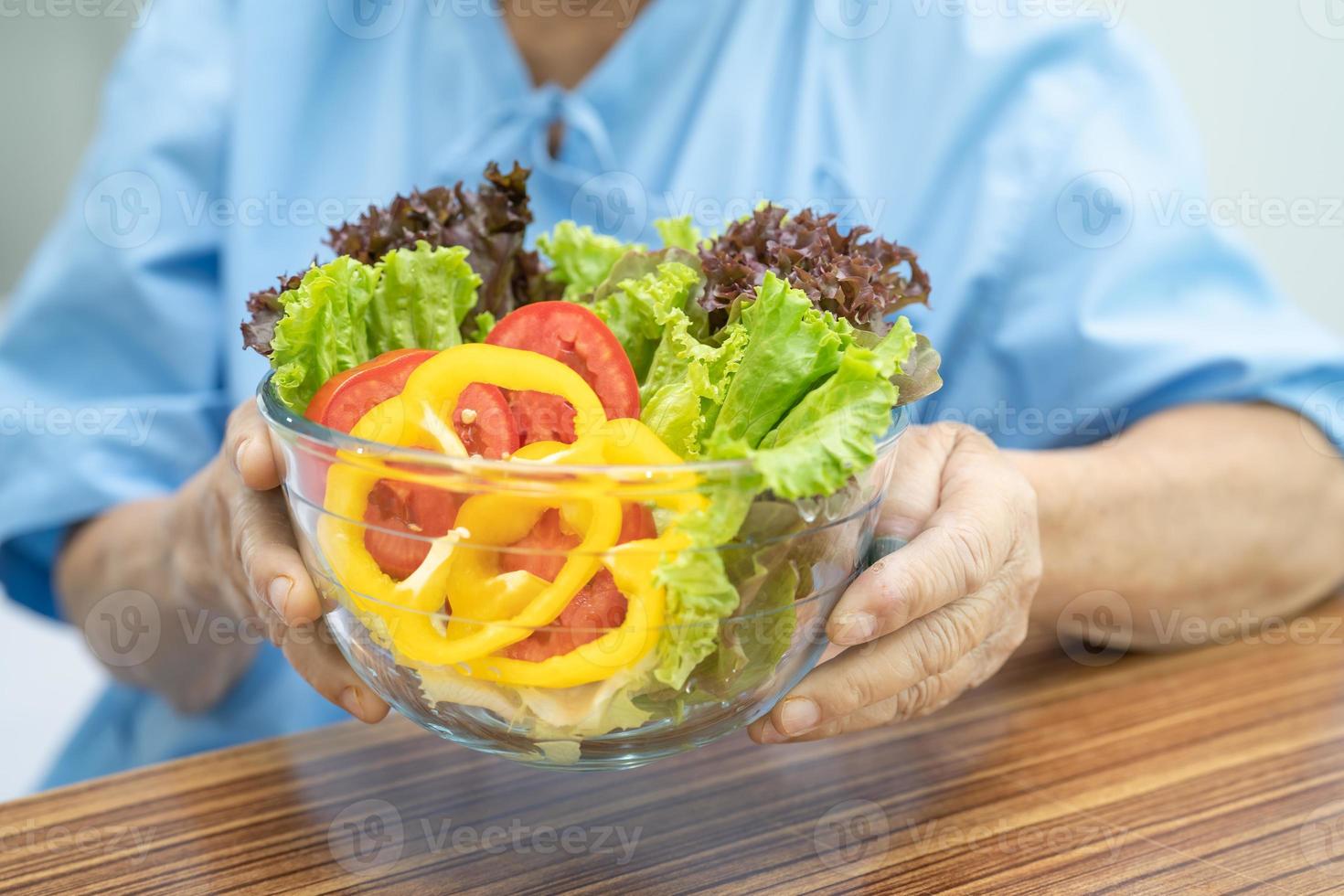 Une patiente asiatique âgée ou âgée de vieille dame mangeant un petit-déjeuner de légumes sains avec espoir et heureuse assise et affamée sur son lit à l'hôpital. photo