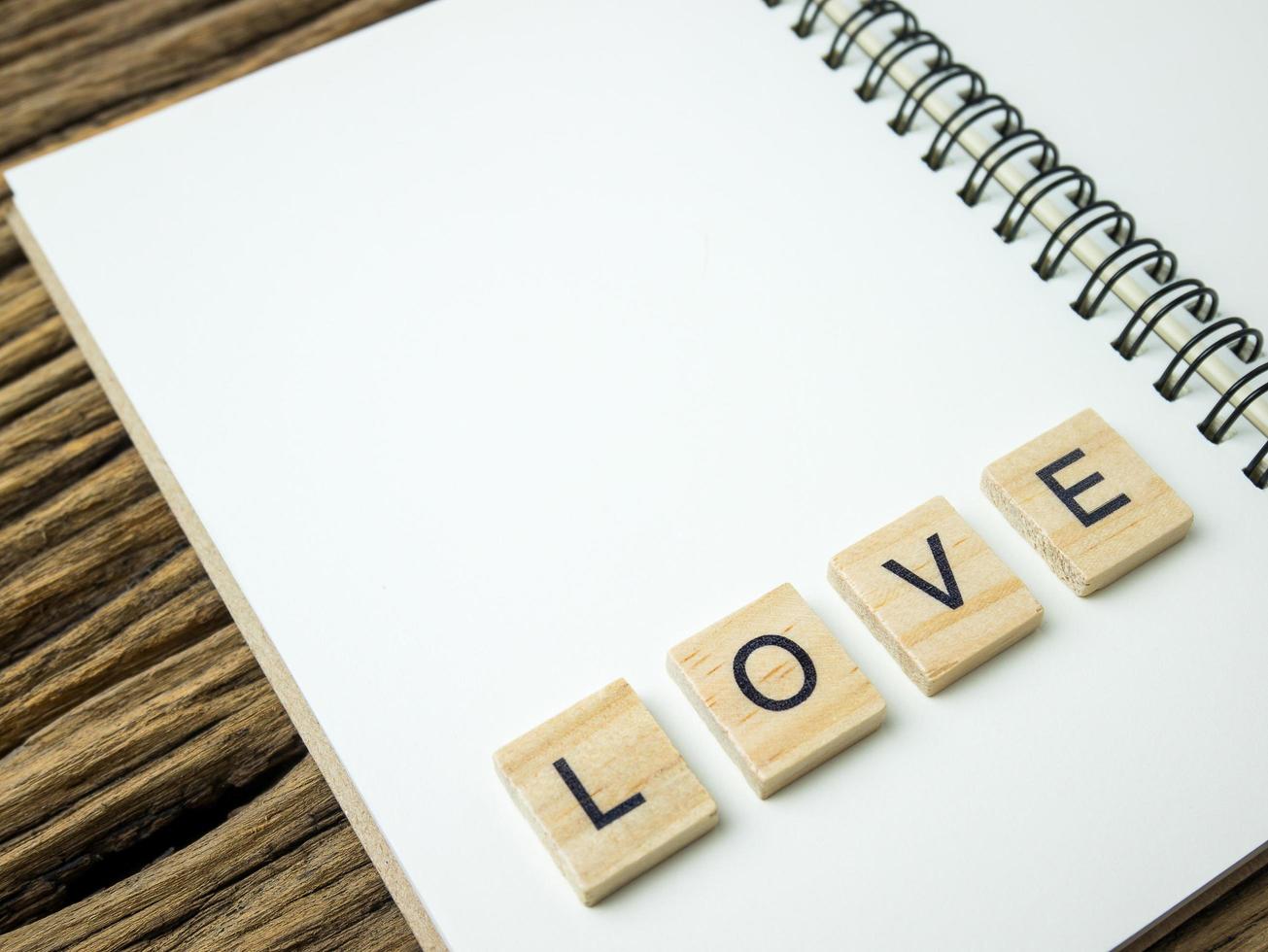 mot d'amour dans un cube en bois et un cahier et un stylo sur fond noir en bois, saint valentin photo