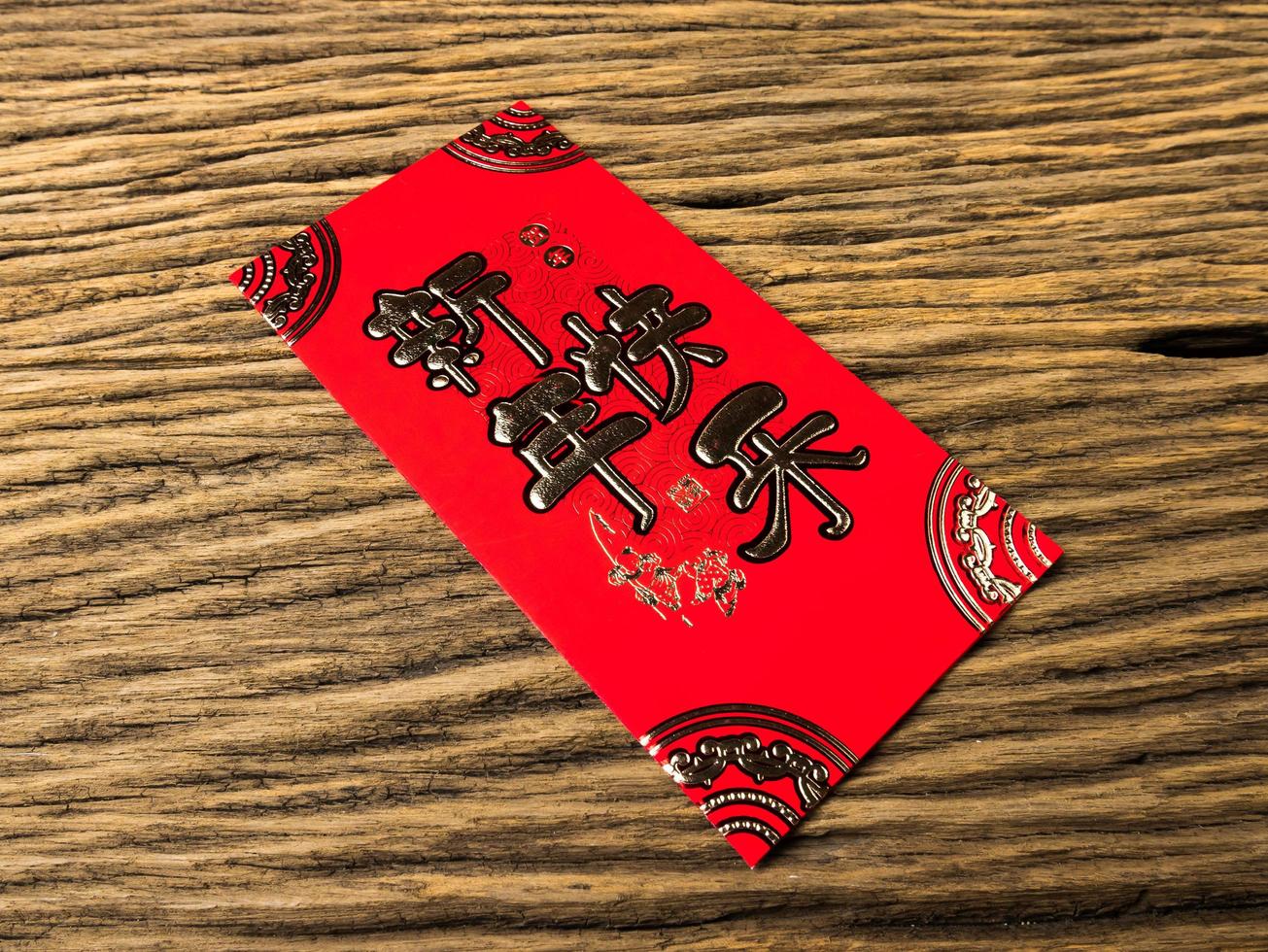 enveloppe rouge sur fond en bois avec février pour cadeau nouvel an chinois. texte chinois sur enveloppe signifiant joyeux nouvel an chinois photo