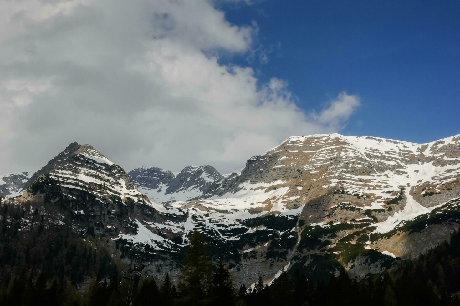 neigeux montagnes avec dense des nuages sur bleu ciel pendant randonnée photo