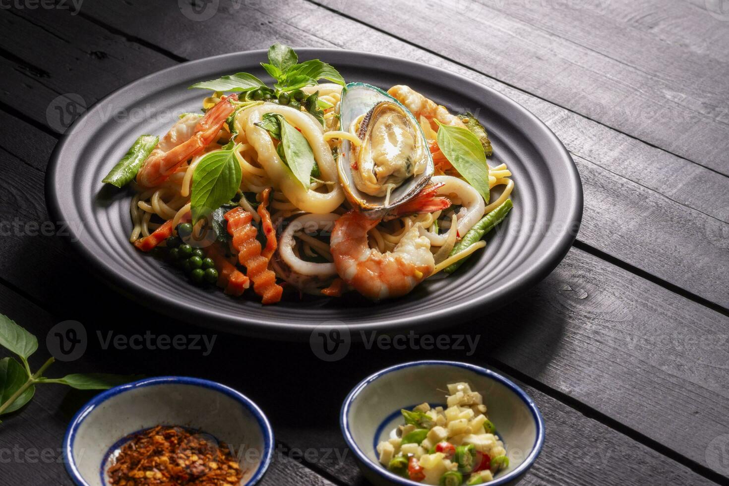 Fruit de mer ivre spaghetti avec crevette calamar palourdes le Chili, et basilic. thaïlandais aliments. en bonne santé asiatique dans une assiette sur une noir Contexte tableau. Haut voir. photo
