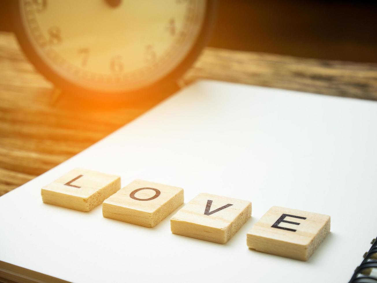 mot d'amour dans un cube en bois et un cahier et un stylo sur fond noir en bois, saint valentin, filtre vintage photo