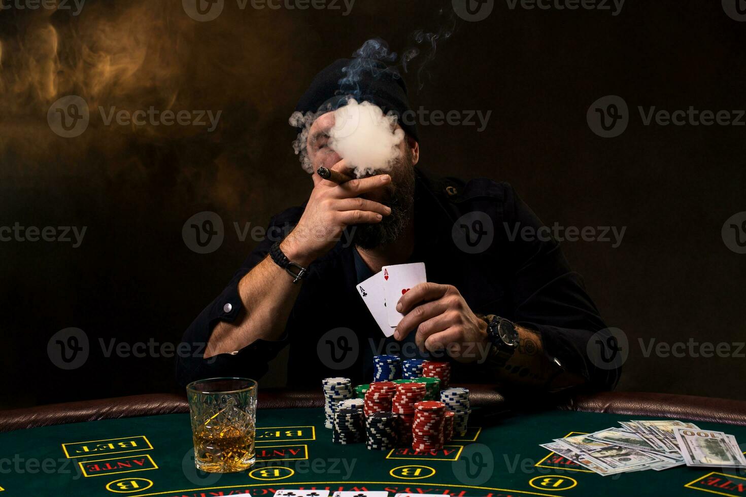 barbu homme avec cigare et verre séance à poker table dans une casino. jeu, en jouant cartes et roulette. photo