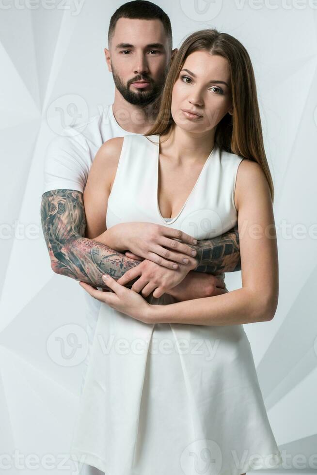 Jeune décontractée couple avec femme en portant le sien mains plus de femme épaule et à la recherche pour le caméra. sur blanc Contexte photo