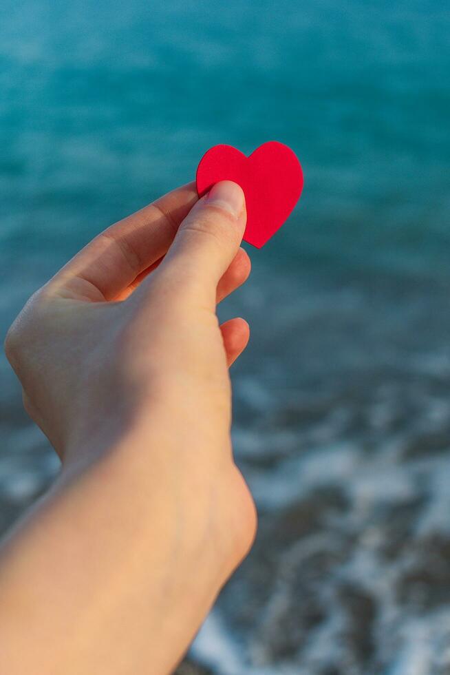 rouge cœur dans une homme main sur le Contexte de le mer horizon. photo