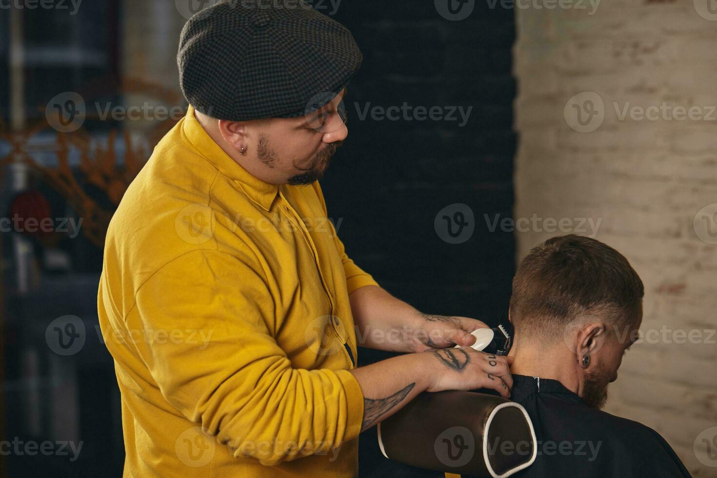 Barbier faisant la coupe de cheveux d'un homme barbu attrayant en salon de coiffure photo