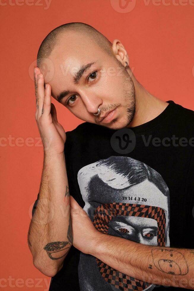 studio coup de une Jeune tatoué chauve homme posant contre une rose Contexte. Années 90 style. photo