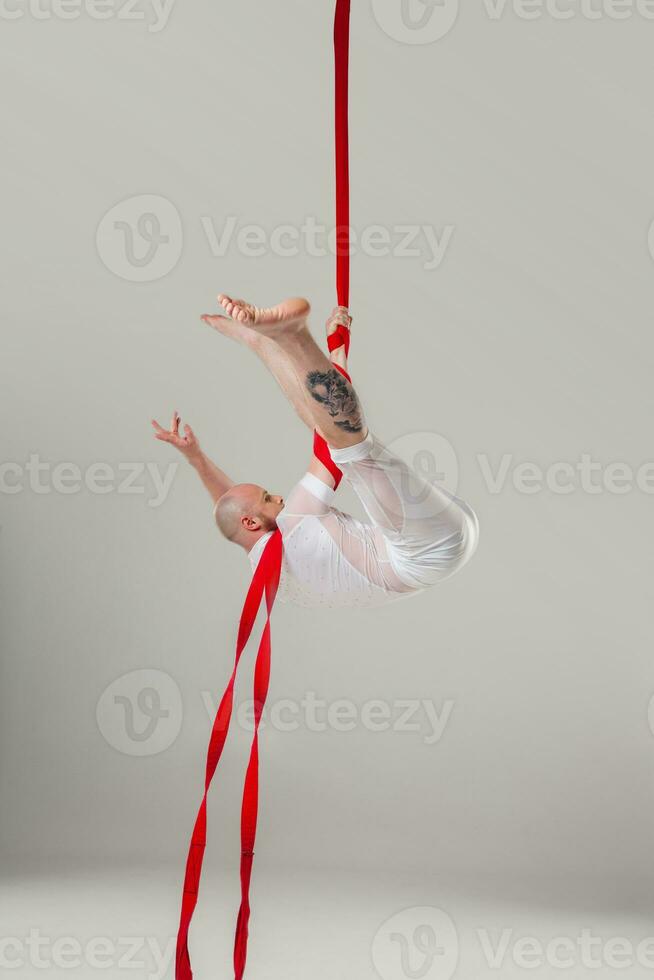 athlétique homme dans une blanc sport costume est performant un acrobatique éléments dans une studio. photo