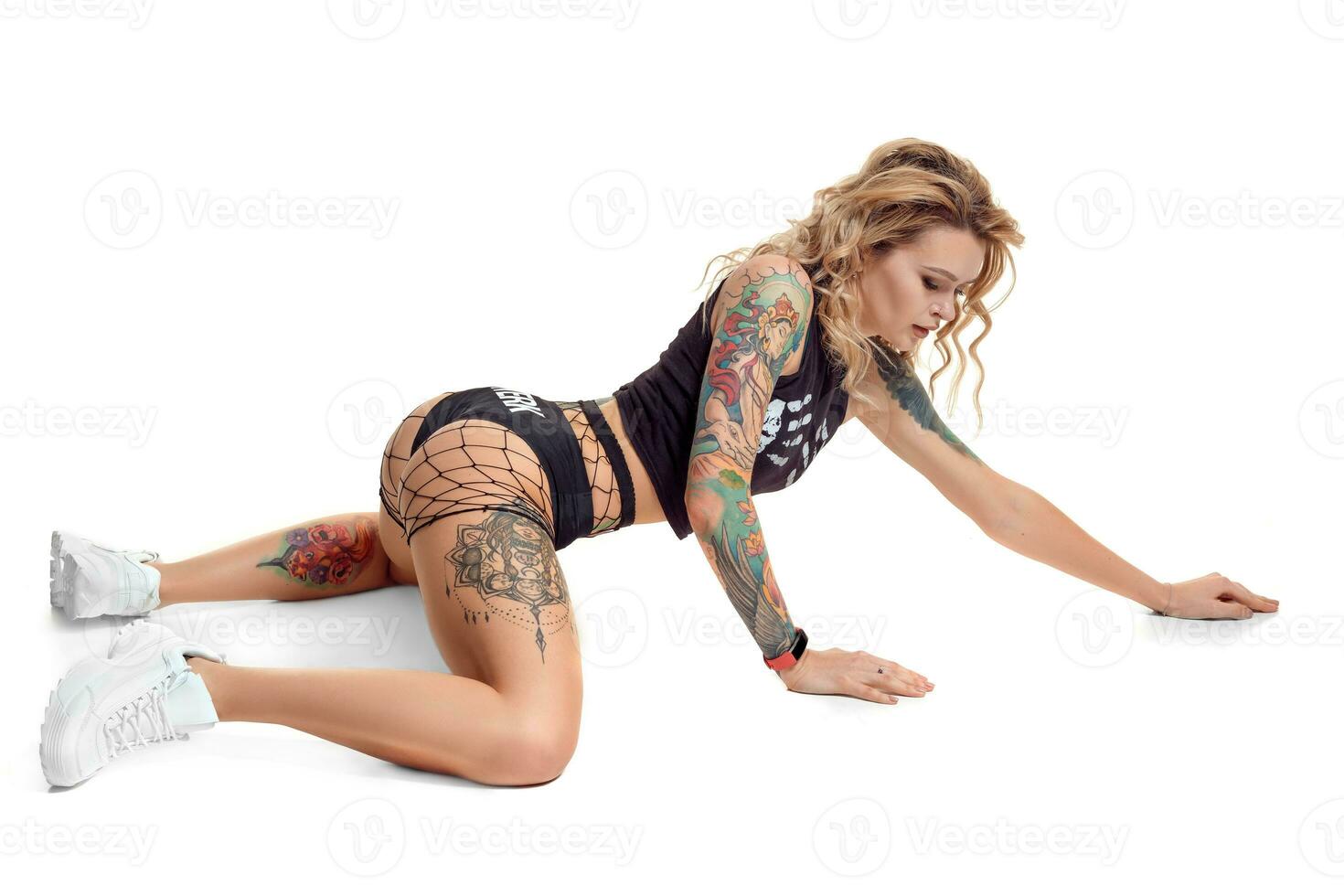 sexy blond twerk femme avec tatoué corps et longue frisé cheveux est posant dans studio. photo