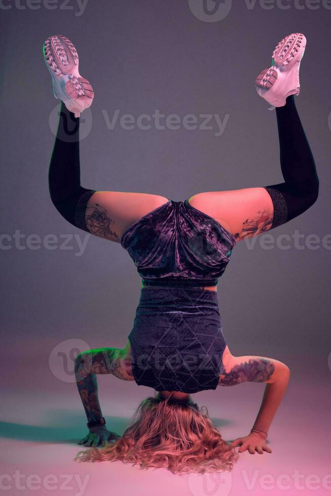 Jeune magnifique blond gymnaste fille dans velours bleu butin short et noir bas permanent à l'envers vers le bas sur rose Contexte photo