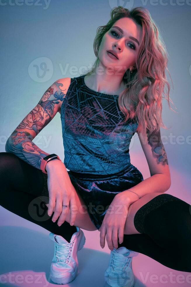 Jeune aptitude blond femme portant bleu velours butin short squats dans de face de caméra, à la recherche à caméra, rose et bleu Contexte photo