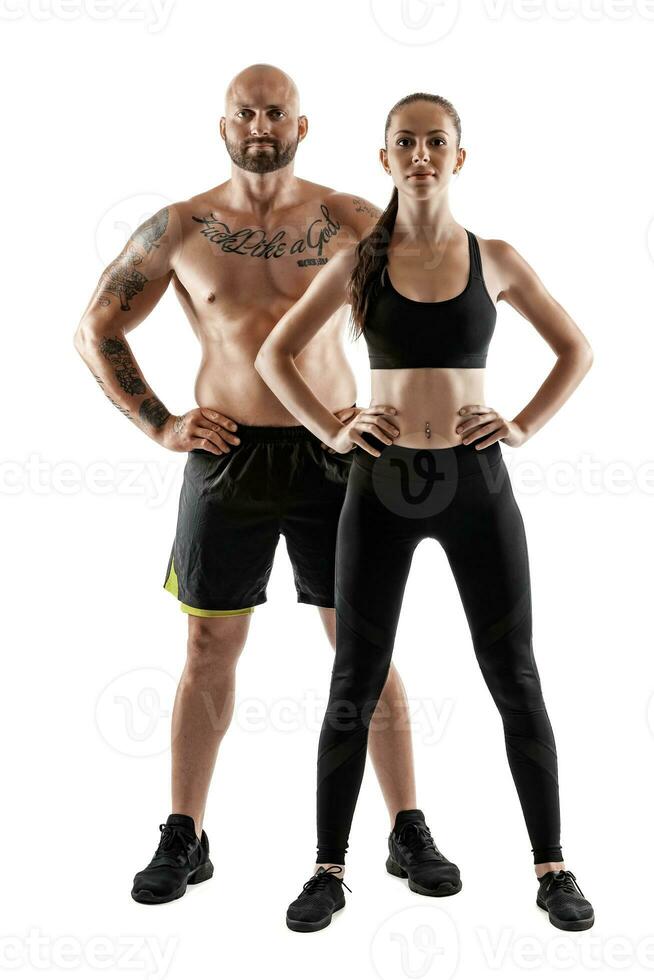 athlétique homme dans noir short et baskets avec brunette femme dans leggings et Haut posant isolé sur blanc Contexte. aptitude couple, Gym concept. photo