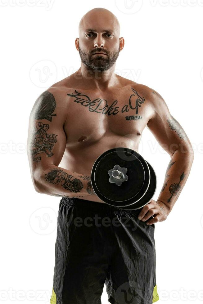 athlétique chauve, tatoué homme dans noir short est posant avec une haltère isolé sur blanc Contexte. fermer portrait. photo