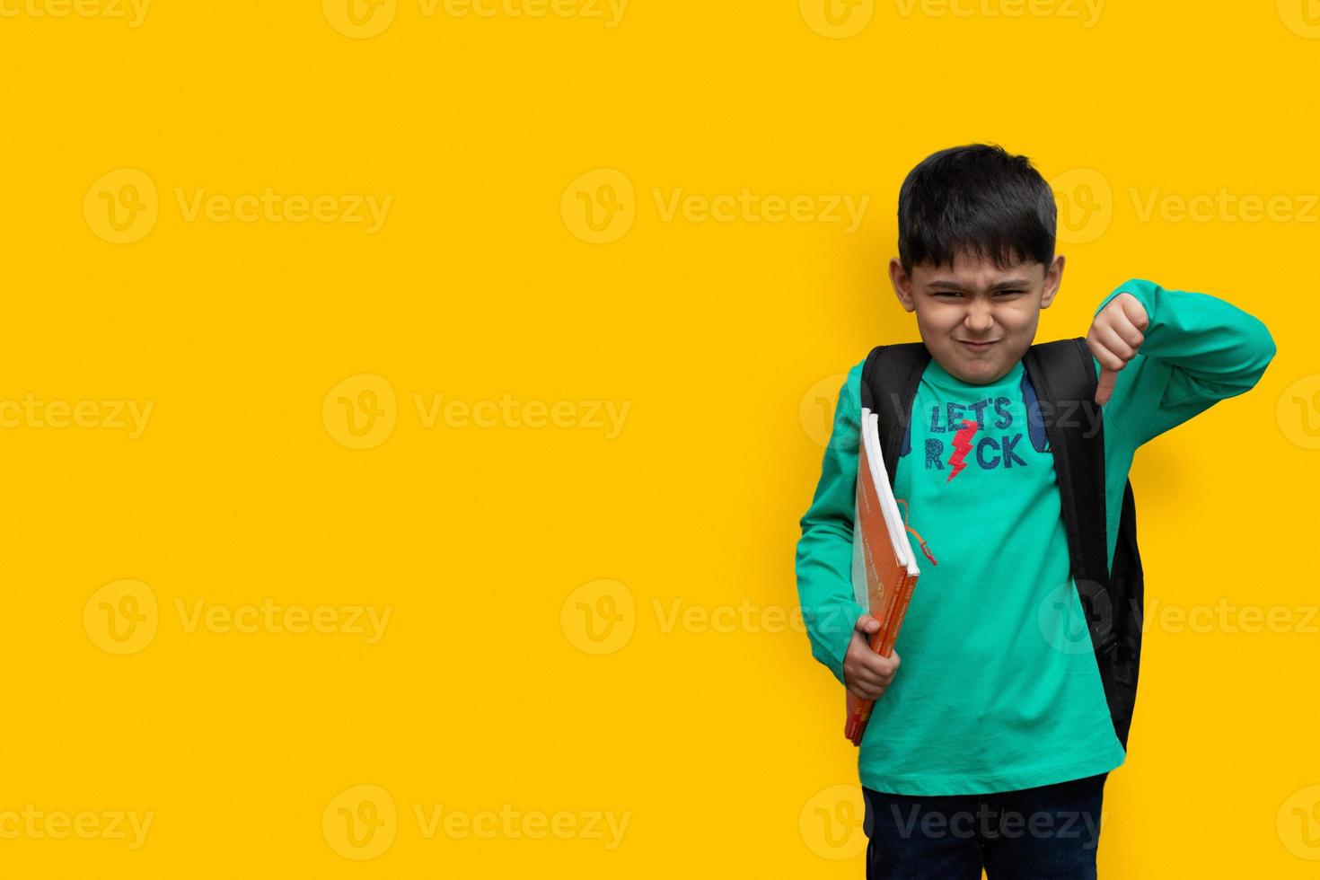 triste enfant garçon avec des livres à la main et un sac sur les épaules, espace de copie de concept d'étude de haine photo