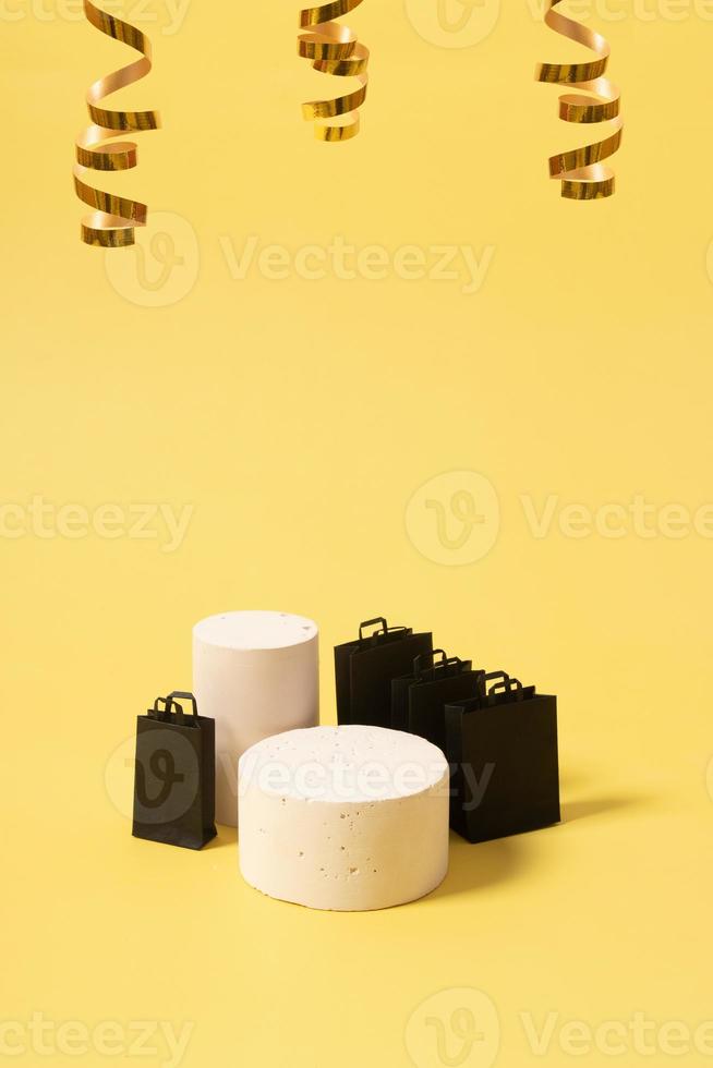 podium ou piédestal vide et sacs à provisions noirs en vente de vendredi noir sur fond jaune photo