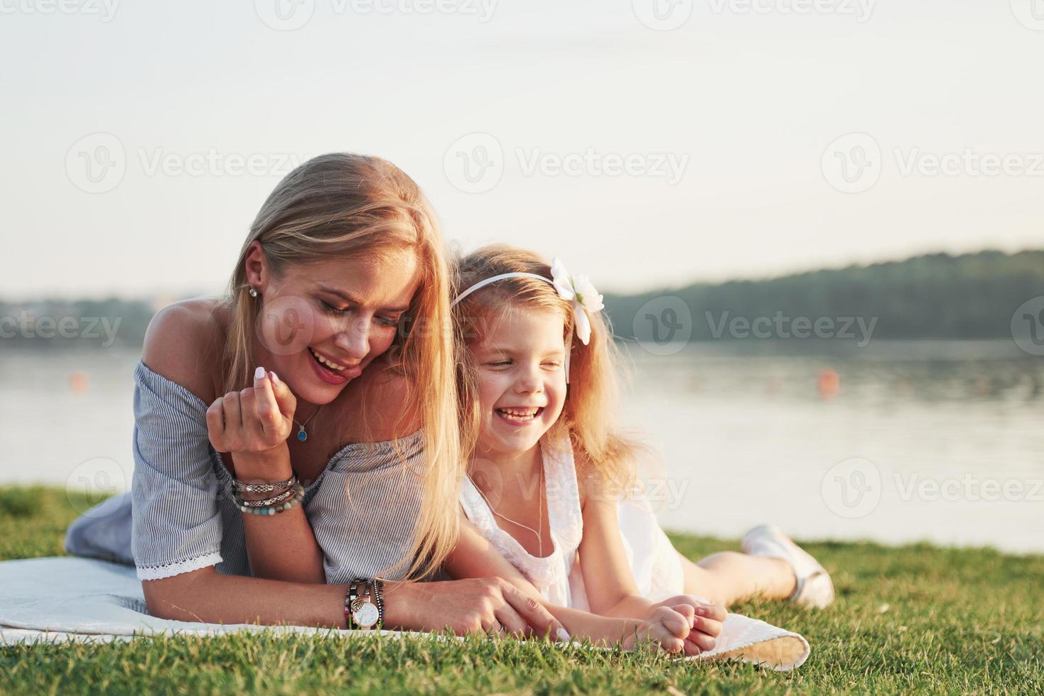 jolie jeune mère heureuse allongée avec sa jolie fille sur l'herbe dans le parc. photo