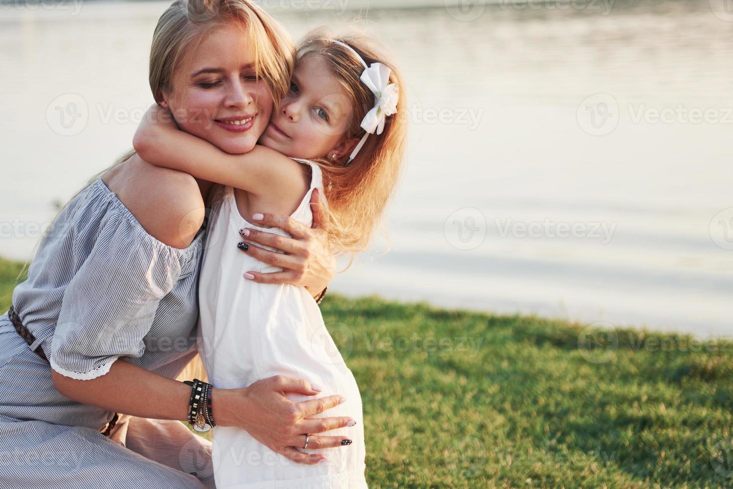 heureuse jeune mère avec une fille enjouée dans un parc près de l'eau photo