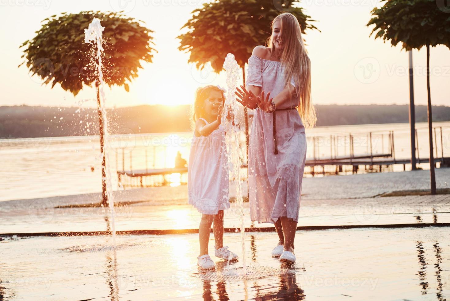 mère avec bébé près de la fontaine au coucher du soleil photo