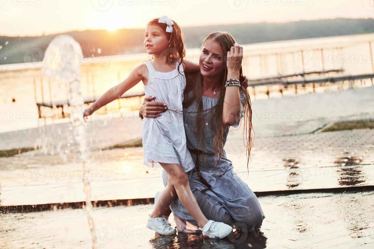 une femme jouant avec un enfant près de l'océan dans le parc au coucher du soleil photo