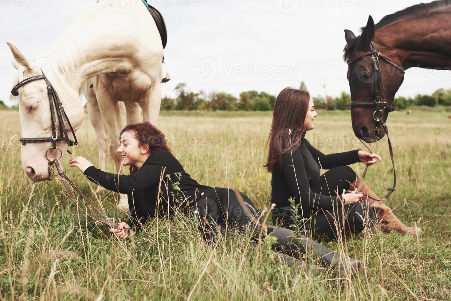 deux belles jeunes filles en train de monter près de leurs chevaux. ils aiment les animaux photo