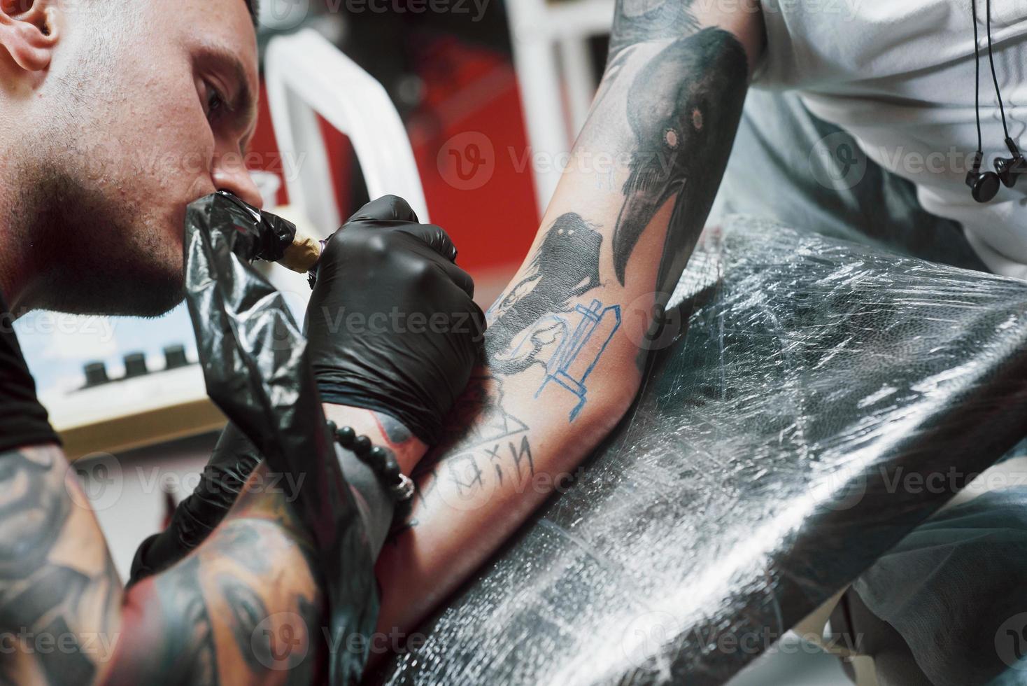 fermer la machine à tatouer. maître en gants stériles noirs créant une image à portée de main avec lui dans le salon photo