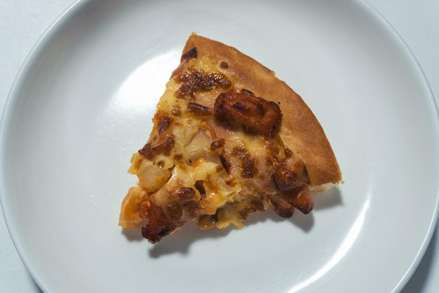 Haut vue proche en haut de une tranché saucisse et fromage Pizza sur blanc assiette avec blanc Contexte photo