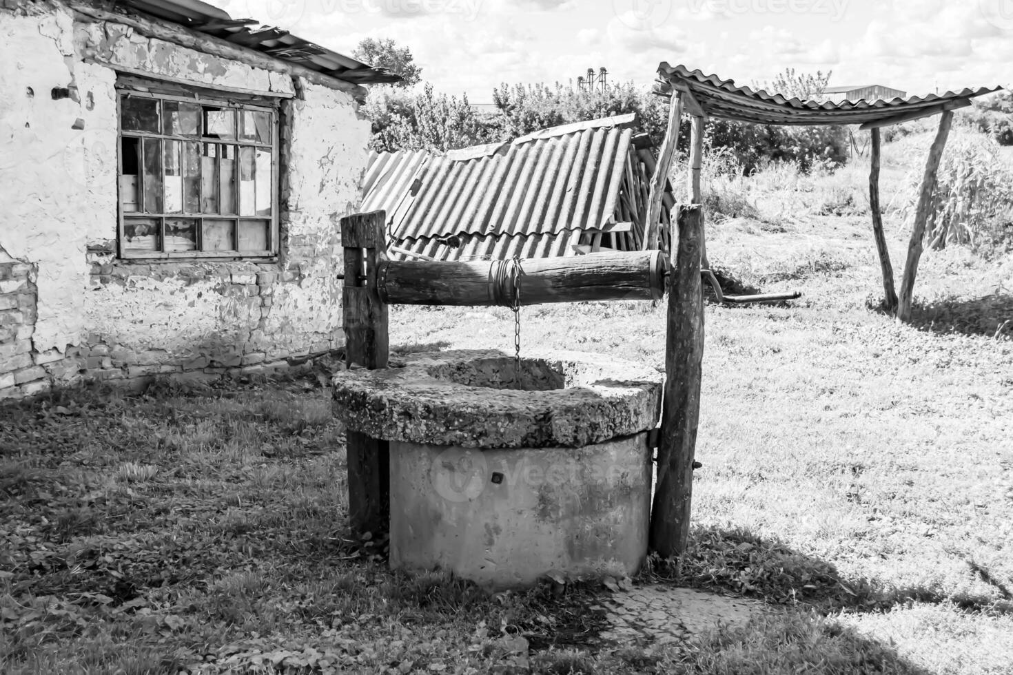 Vieux puits avec seau en fer sur longue chaîne forgée pour l'eau potable photo