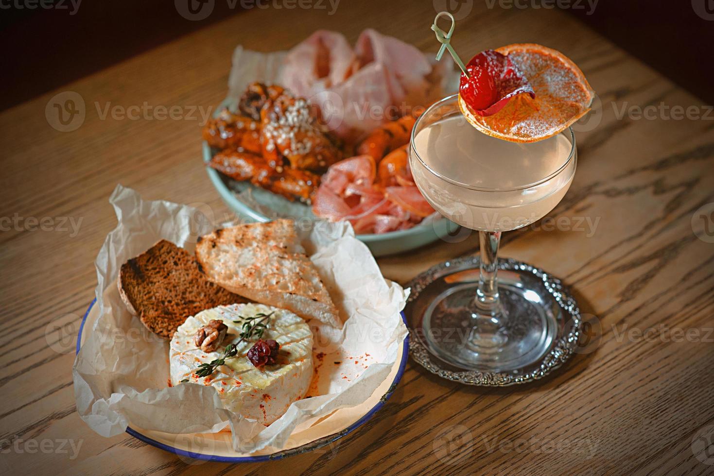 assiette de viande appétissante avec saucisse, jambon, jambon, camembert au four et décor de cocktail d'alcool photo