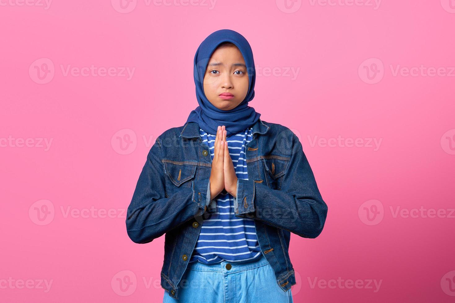 portrait de tristesse jeune femme asiatique montrant un geste de prière sur fond rose photo