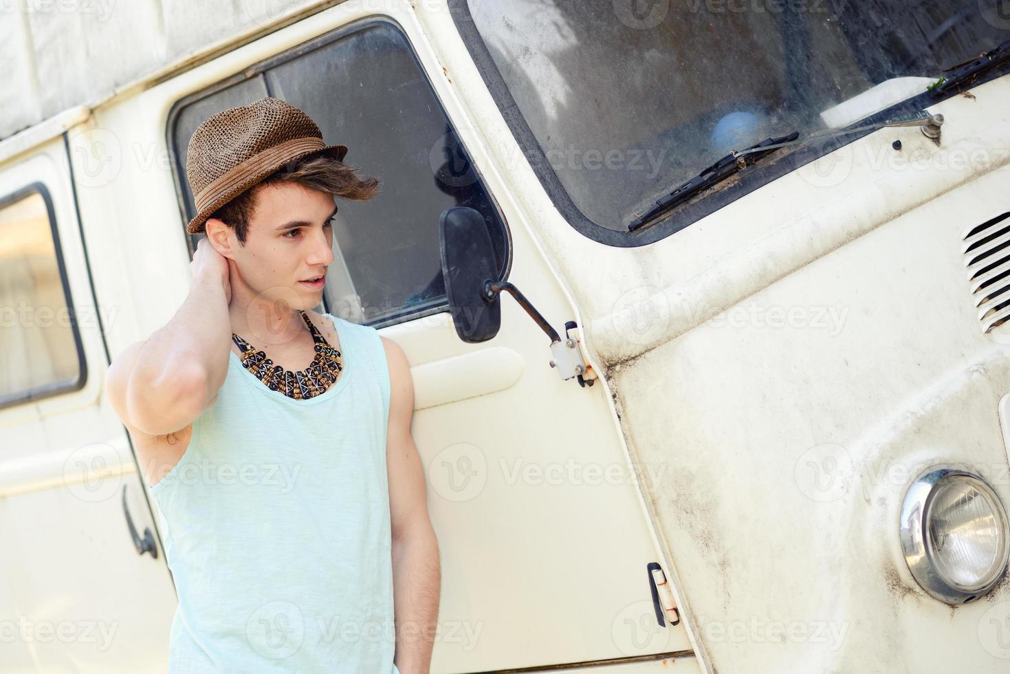 Jeune bel homme avec une vieille camionnette portant un chapeau de soleil photo