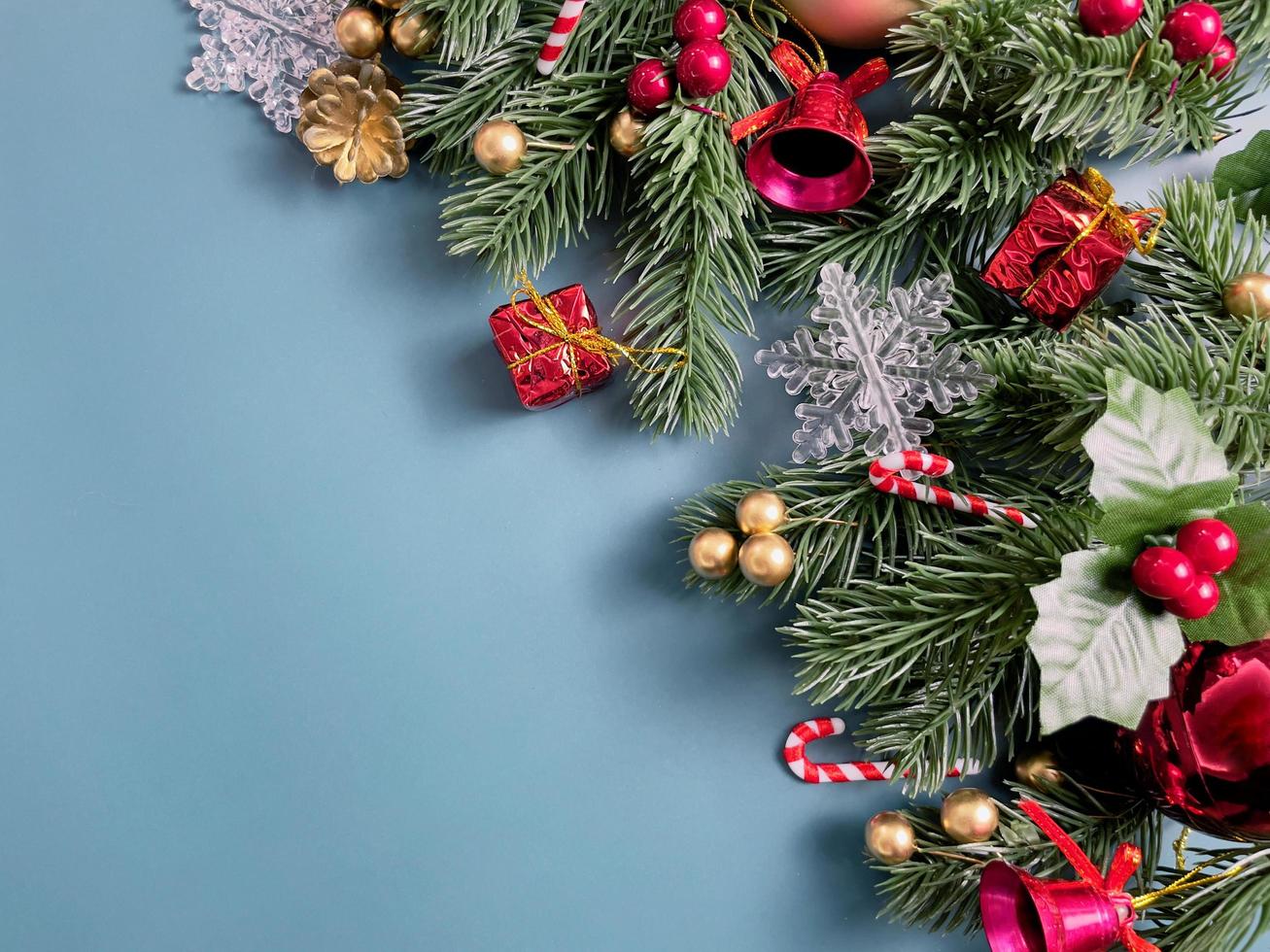 décorations de noël, feuilles de pin, boules dorées, flocons de neige, baies rouges et baies dorées sur fond bleu photo