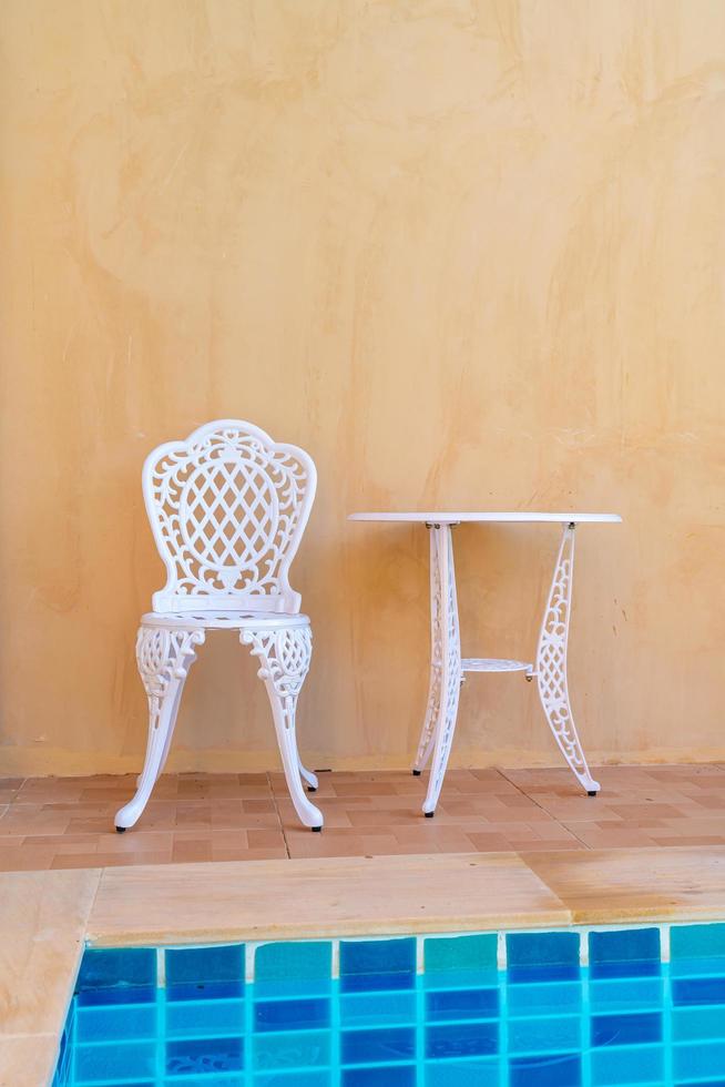 chaise et table blanches vides du côté de la piscine photo