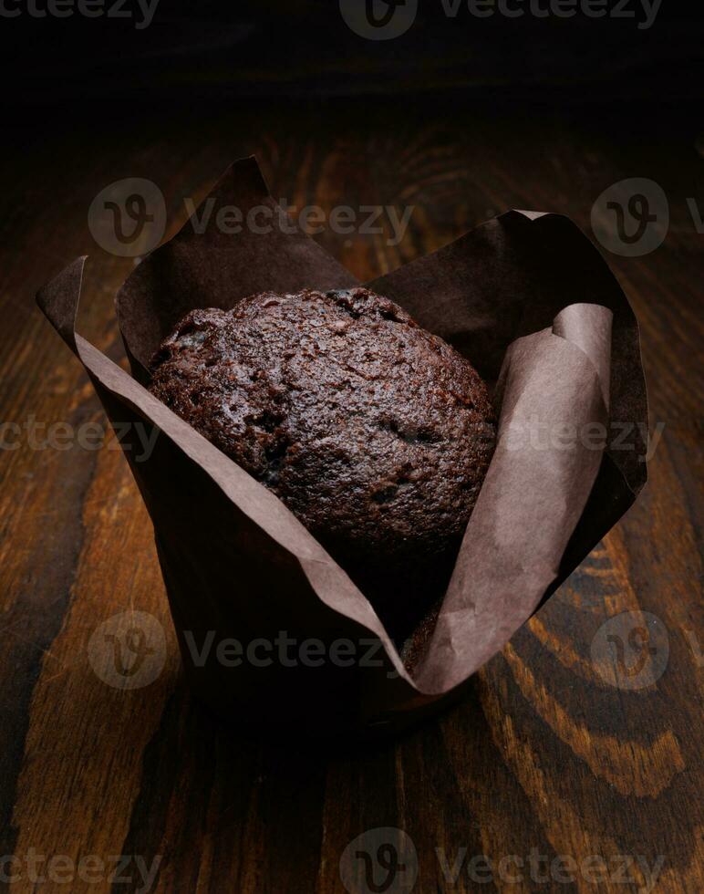 Chocolat petit gâteau sur une foncé Contexte. muffin avec Chocolat frites sur une en bois surface. photo