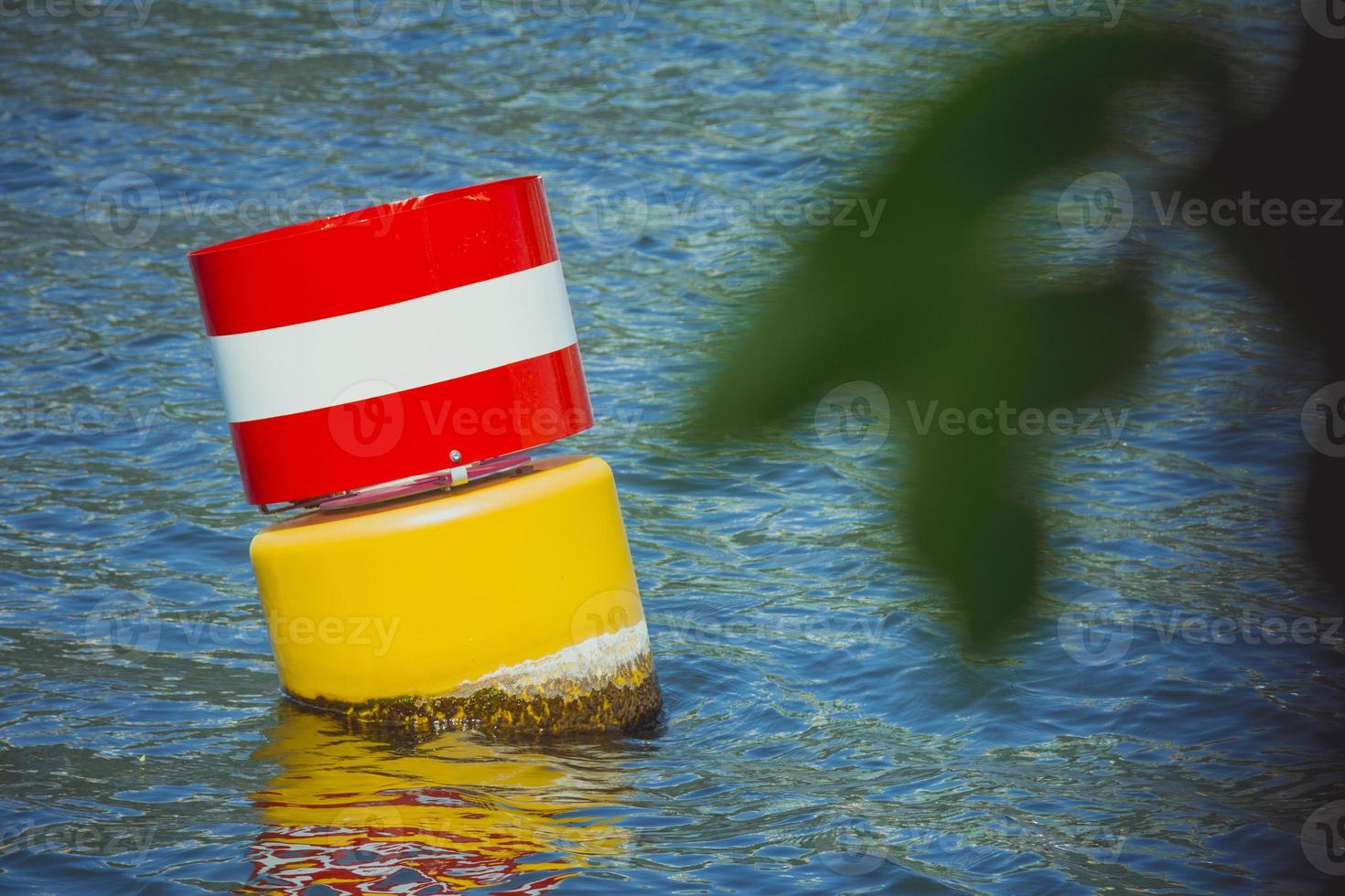 bouée flottante de navigation en acier jaune rouge et blanc dans l'eau de mer bleue photo