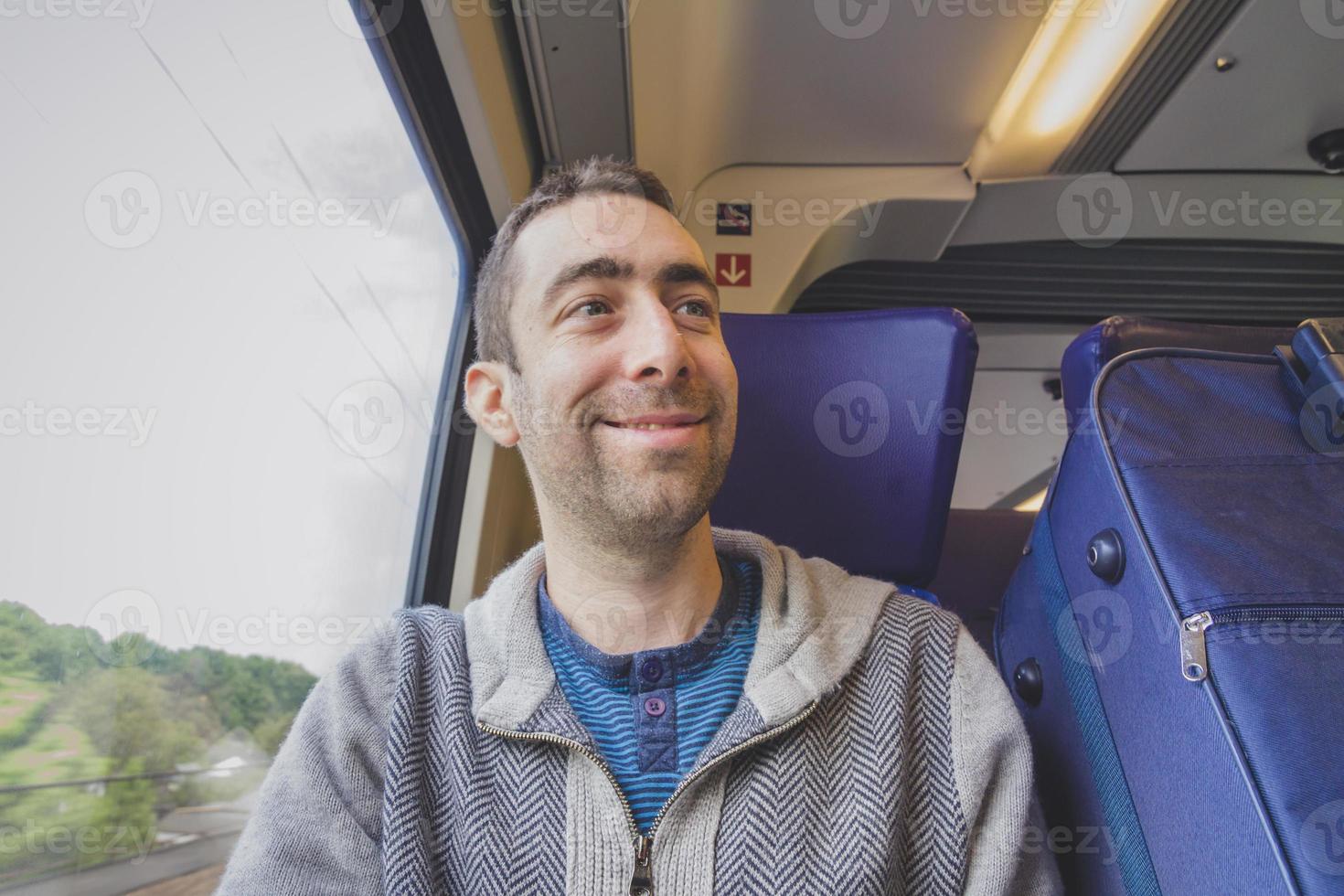 jeune homme voyageant dans un train et souriant à quelqu'un photo