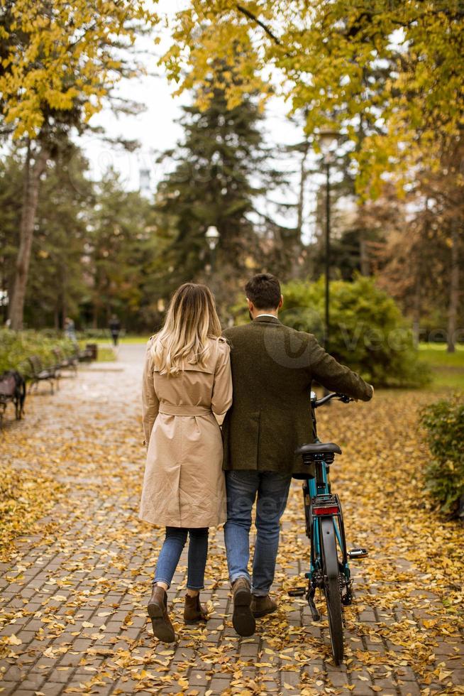 vue arrière au jeune couple dans le parc d'automne avec vélo électrique photo