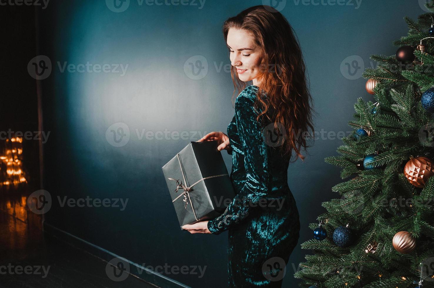 belle fille avec une boîte présente près de l'arbre de noël photo