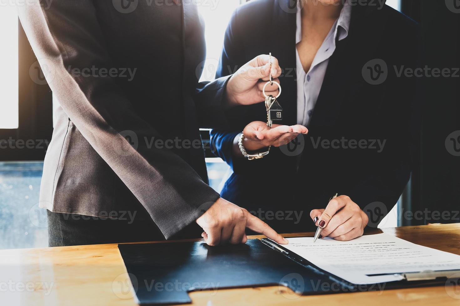 les agents immobiliers acceptent d'acheter une maison et remettent les clés aux clients dans les bureaux de leur agence. accord de concept. photo